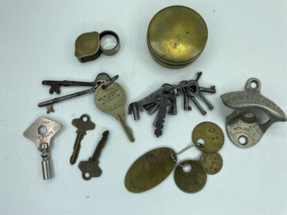 Lot # 81 – Trinket box lot. Vintage Alcatraz prison tags, old keys, casino Monte Carlo brass tin, Coca-Cola wall bottle opener, & more